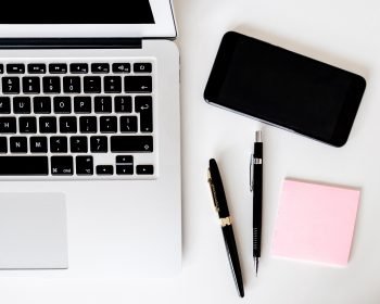 A top down view of a laptop, pen, and sticky notes