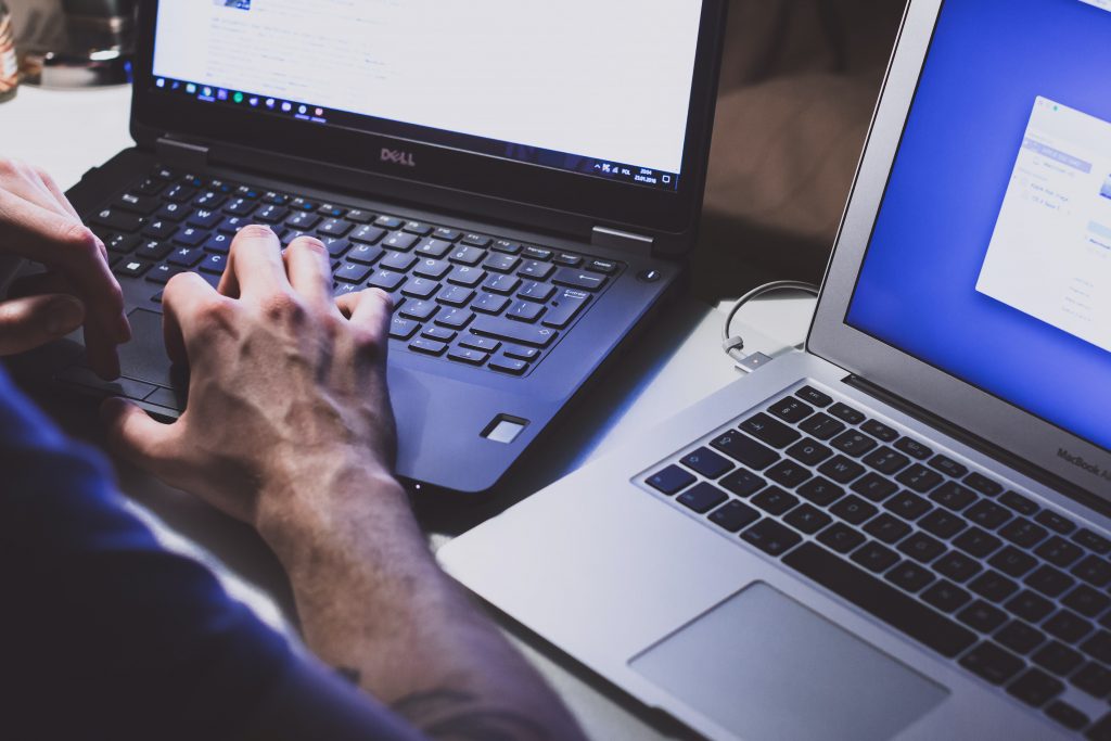 Person working on two laptops