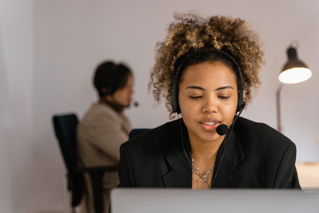 Woman with a headset on talking while looking at laptop