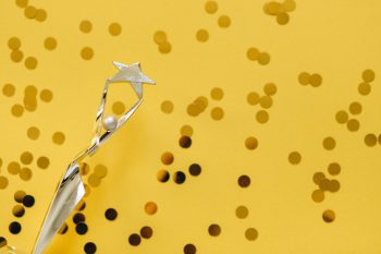 A trophy on top of a yellow background with confetti