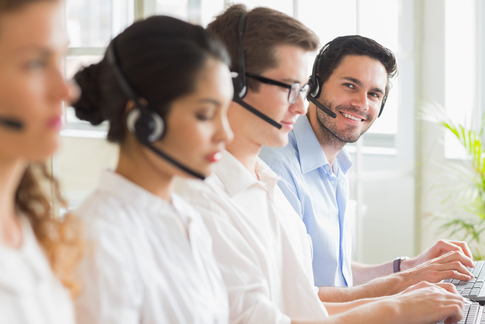 Portrait of happy businessman with colleagues working in call center
